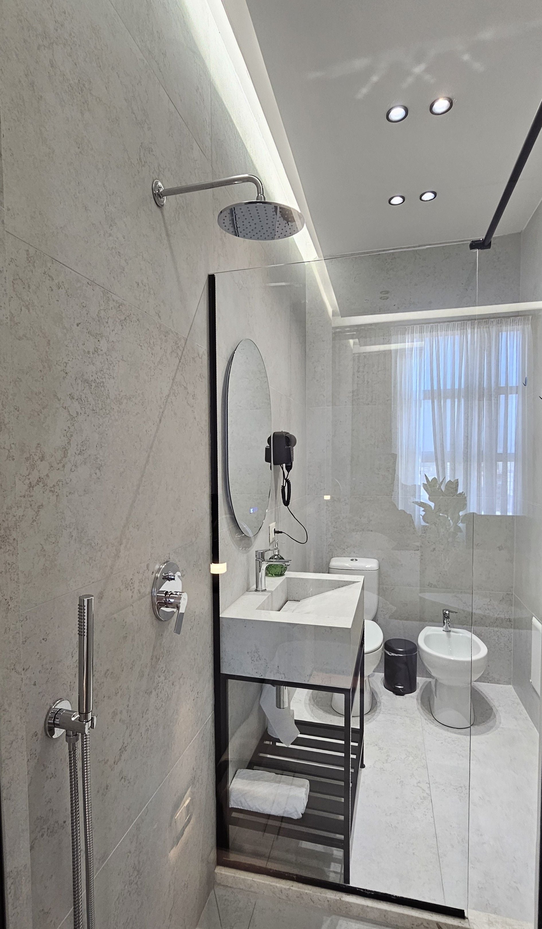 Un baño moderno con ducha envuelta en vidrio, tocador con espejo, inodoro y bidé.