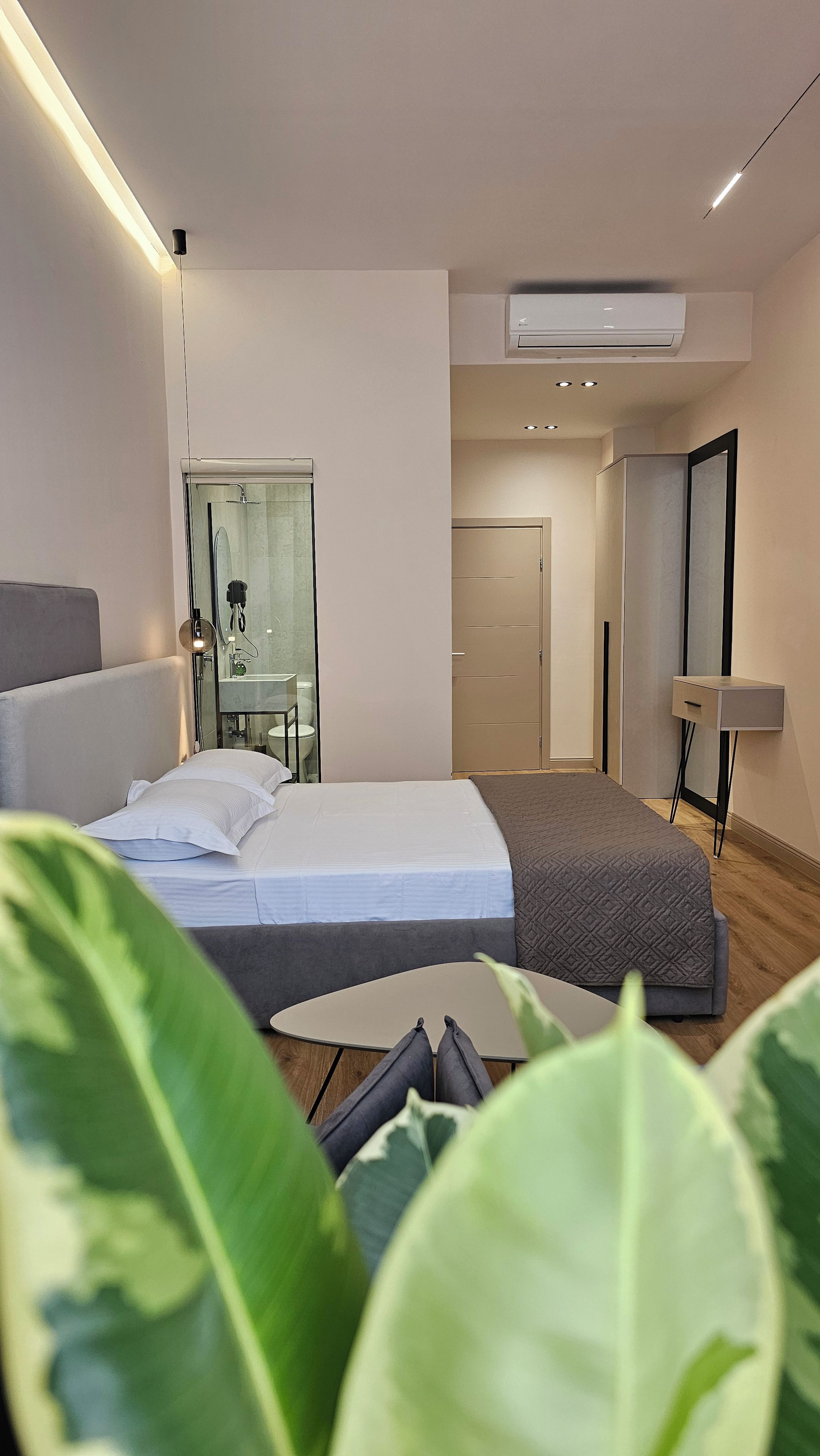 A modern hotel room with a bed, bedside table, and a mirror.