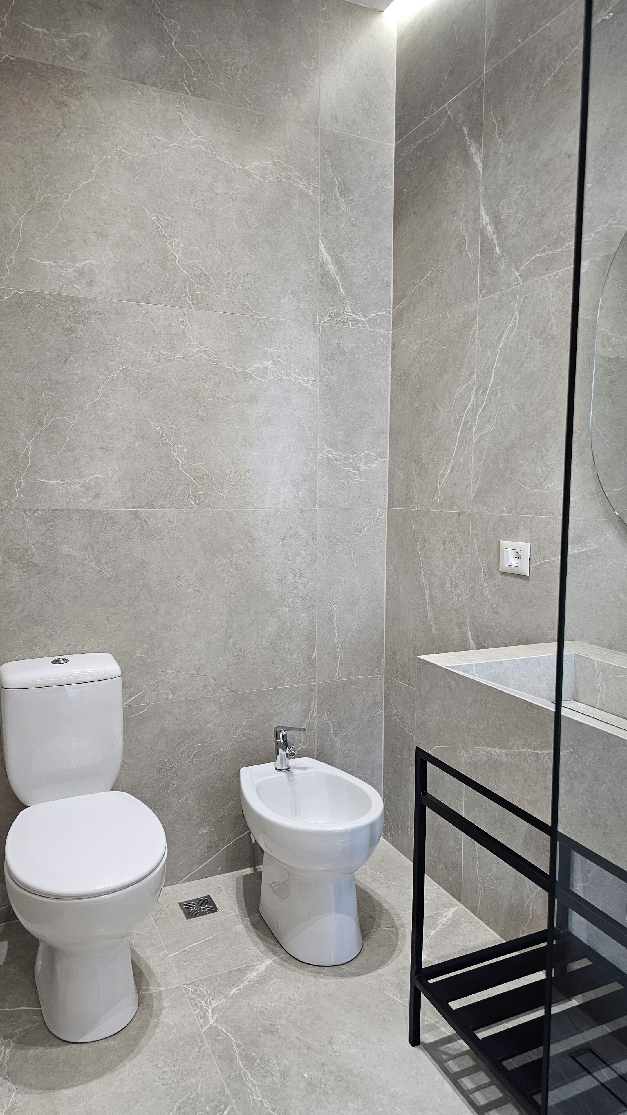 A bathroom with a toilet, bidet, and a glass shower enclosure.