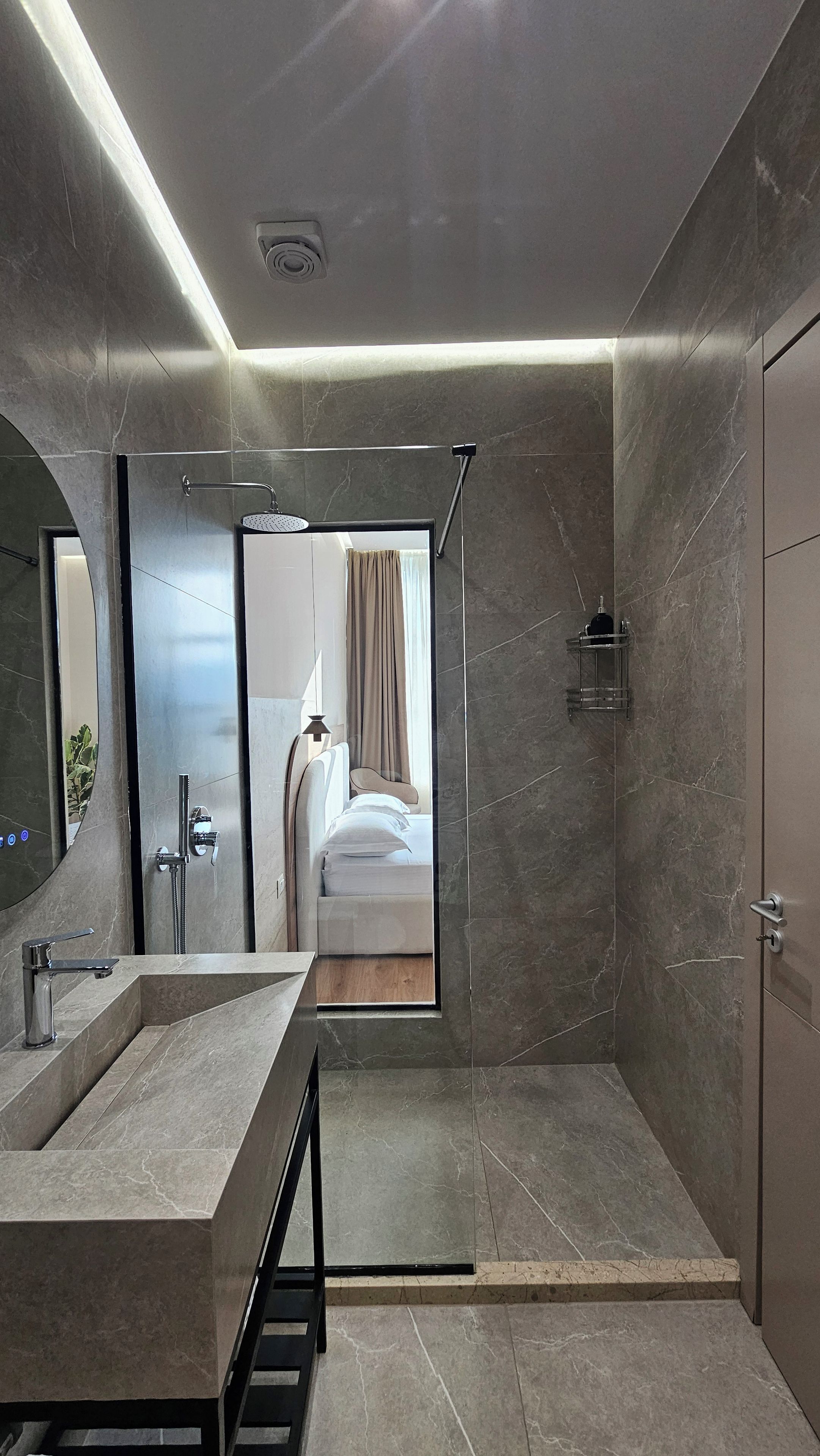 A modern bathroom with a large mirror, a shower area, and a sink.