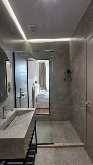 A modern bathroom with a large mirror, a shower area, and a sink. - The Center 102 (Shkodër)