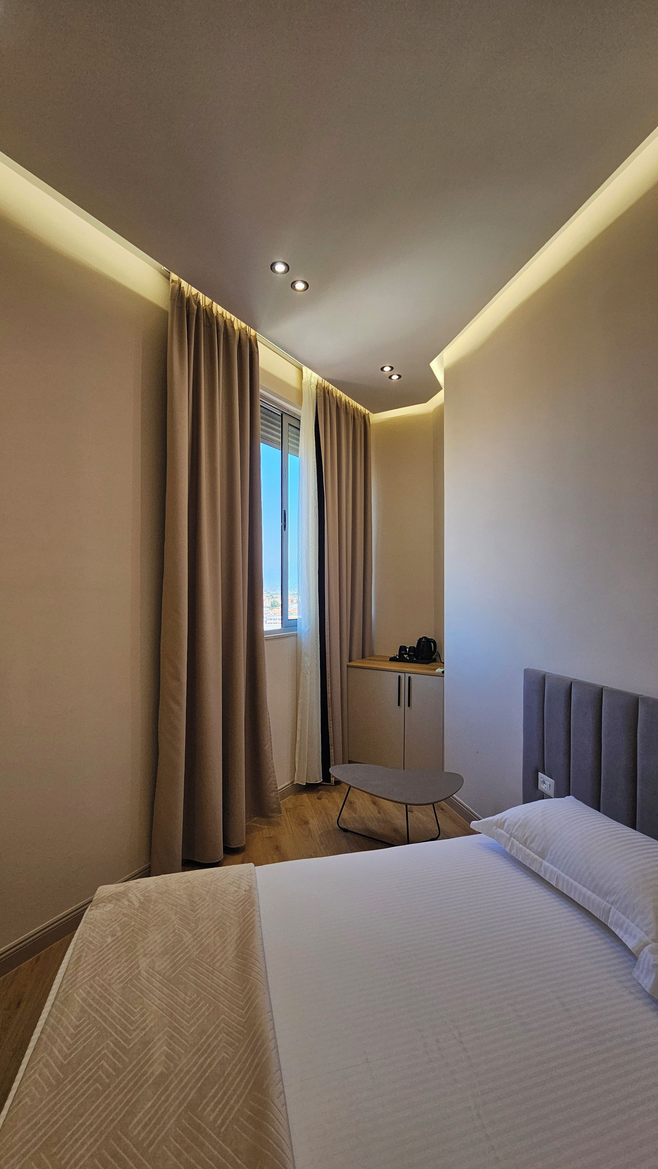A hotel room with a bed, a desk, and a window with curtains.
