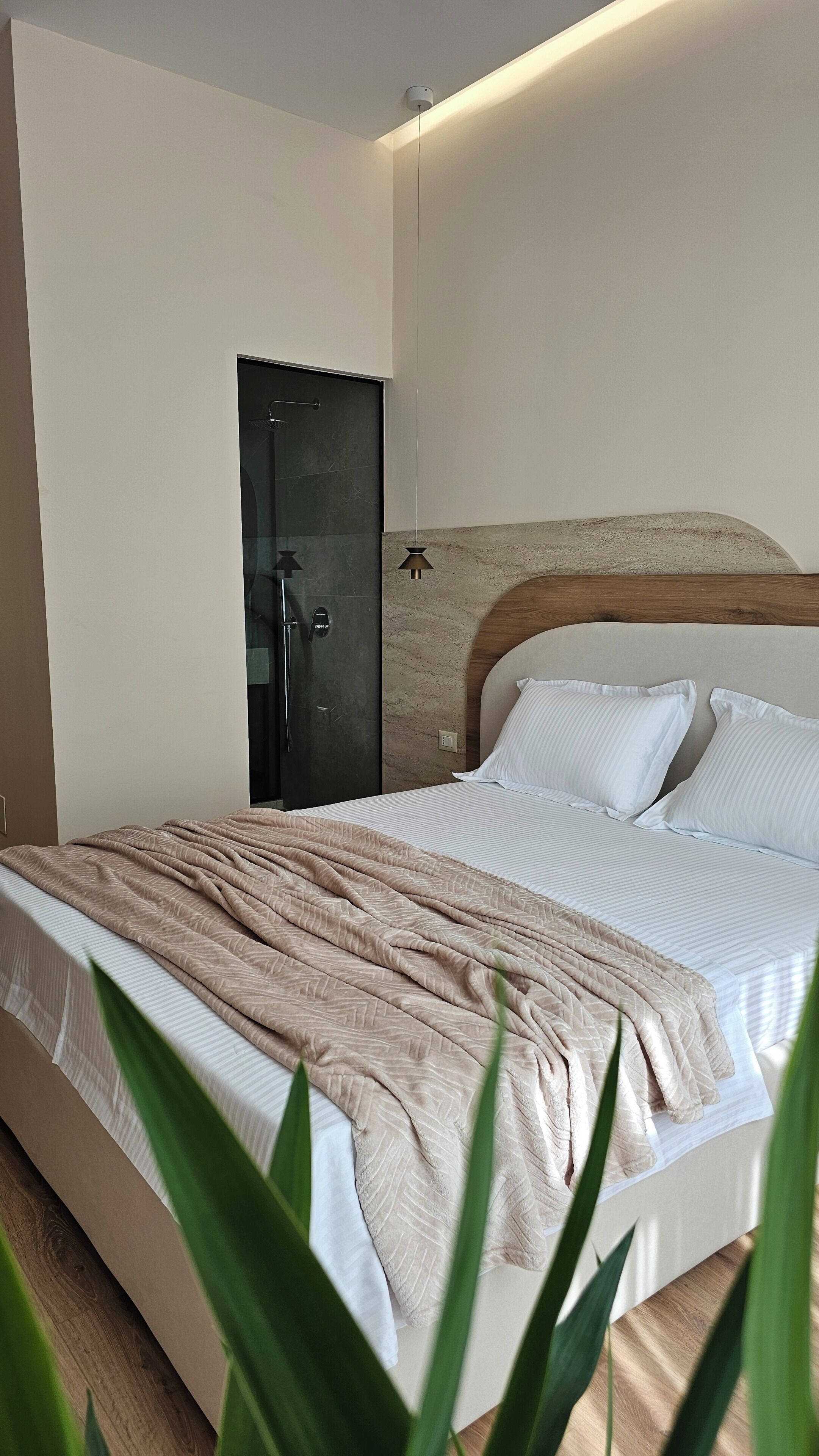 Ein modernes Schlafzimmer mit einem Bett, einem Holzkopfteil, einem Nachttisch und einer Tür.