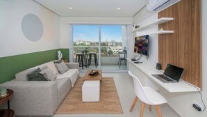 Een moderne woonkamer met een bank, een salontafel, een eettafel en een werkplek met een laptop.