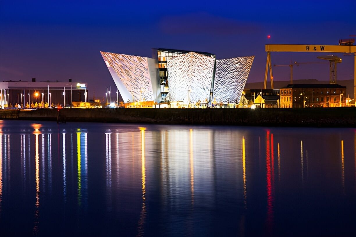 A modern building with a unique angular design, a waterfront location, and a crane in the background.