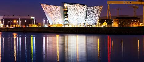 A modern building with a unique angular design, a waterfront location, and a crane in the background.