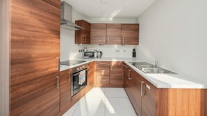 A modern kitchen with wooden cabinets, stainless steel appliances, and a white countertop. - Skyline & Sea (Belfast)
