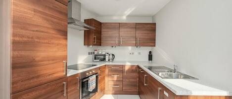 Une cuisine moderne avec des meubles en bois, des appareils en acier inoxydable et un plan de travail blanc.