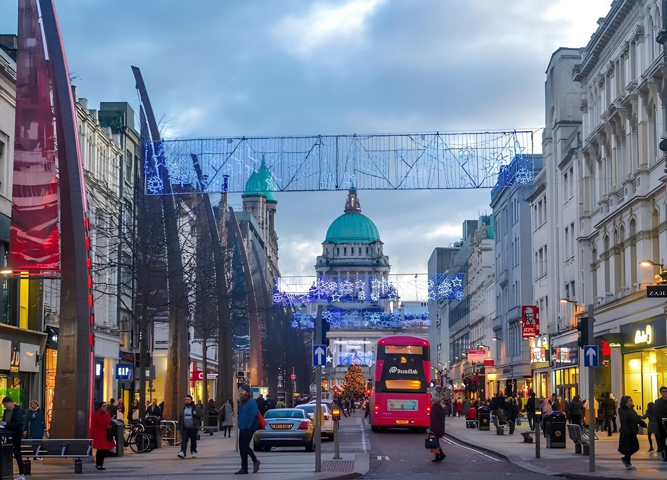 A busy urban street with a prominent building featuring a green dome and a red bus in the foreground.