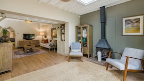 A cozy living room with a fireplace, wooden furniture, and a television. - The Old Bakery - sleeps 6 guests  in 3 bedrooms (Alderminster)
