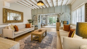 A spacious living room with a large mirror, two sofas, a coffee table, and a dining area. - The Old Bakery - sleeps 6 guests  in 3 bedrooms (Alderminster)