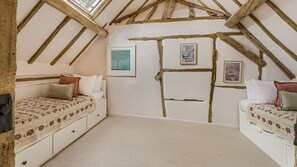 A bedroom with two beds, a sloped ceiling with exposed beams, and three framed artworks on the wall. - The Old Bakery - sleeps 6 guests  in 3 bedrooms (Alderminster)