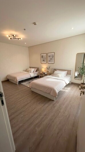 A bedroom with two beds, a bedside table, a nightstand, a mirror, and a ceiling light fixture.