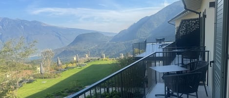 Un balcón con vistas a montañas y un jardín.