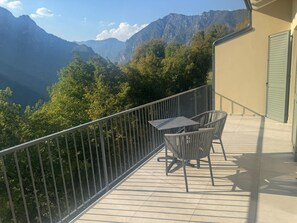 A balcony with a table and chairs overlooking a mountainous landscape. - Apartment 8 – Palermo (Tremosine sul Garda)