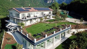 A modern two-story house with a flat roof, solar panels, and a large glass conservatory. - Apartment 8 – Palermo (Tremosine sul Garda)