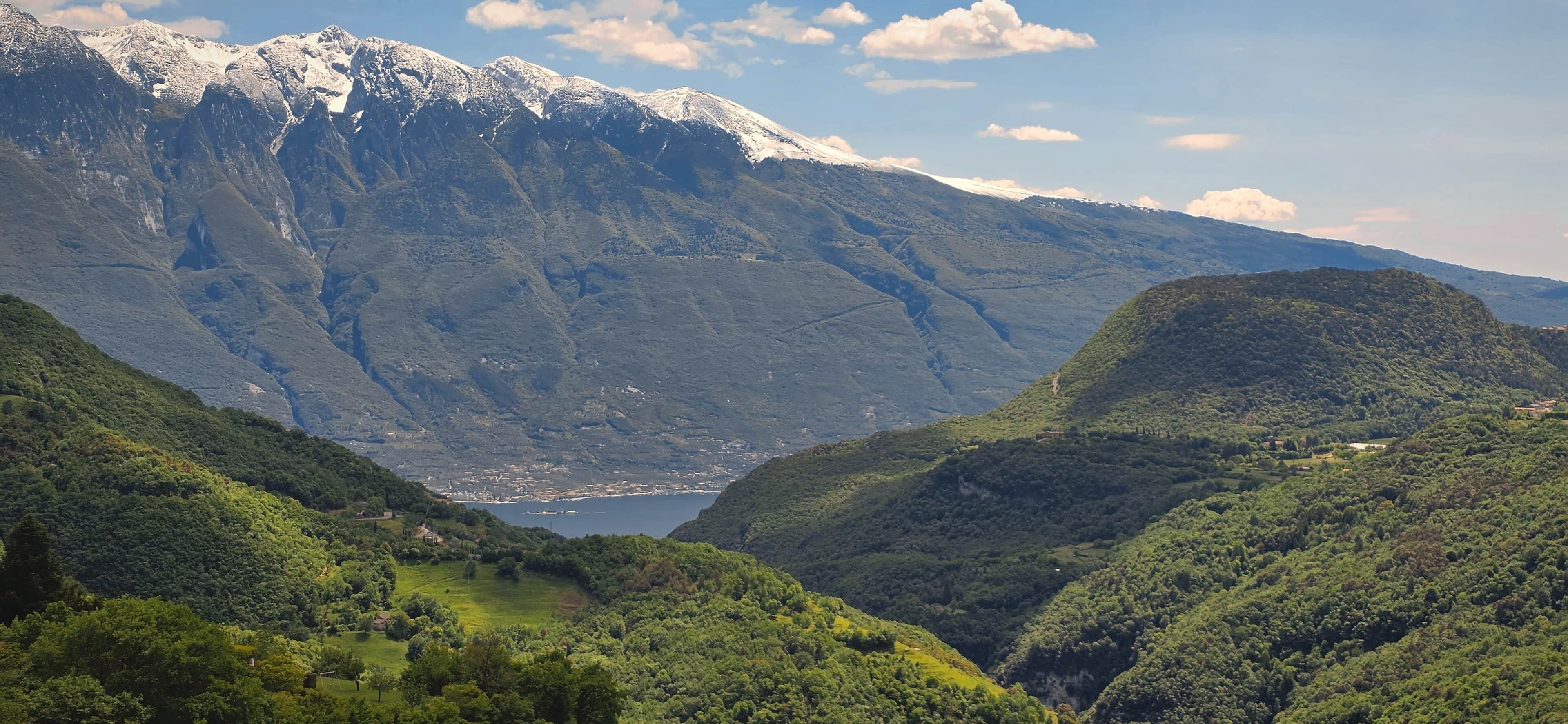 Paisagem montanhosa com um vale, um lago e picos nevados.