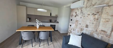 A modern kitchen with a dining table and chairs, a sofa, and a decorative wall.