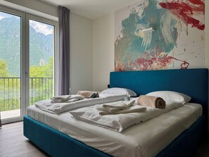 Une chambre à coucher avec un lit, une vue sur les montagnes et un grand tableau abstrait accroché au mur.
