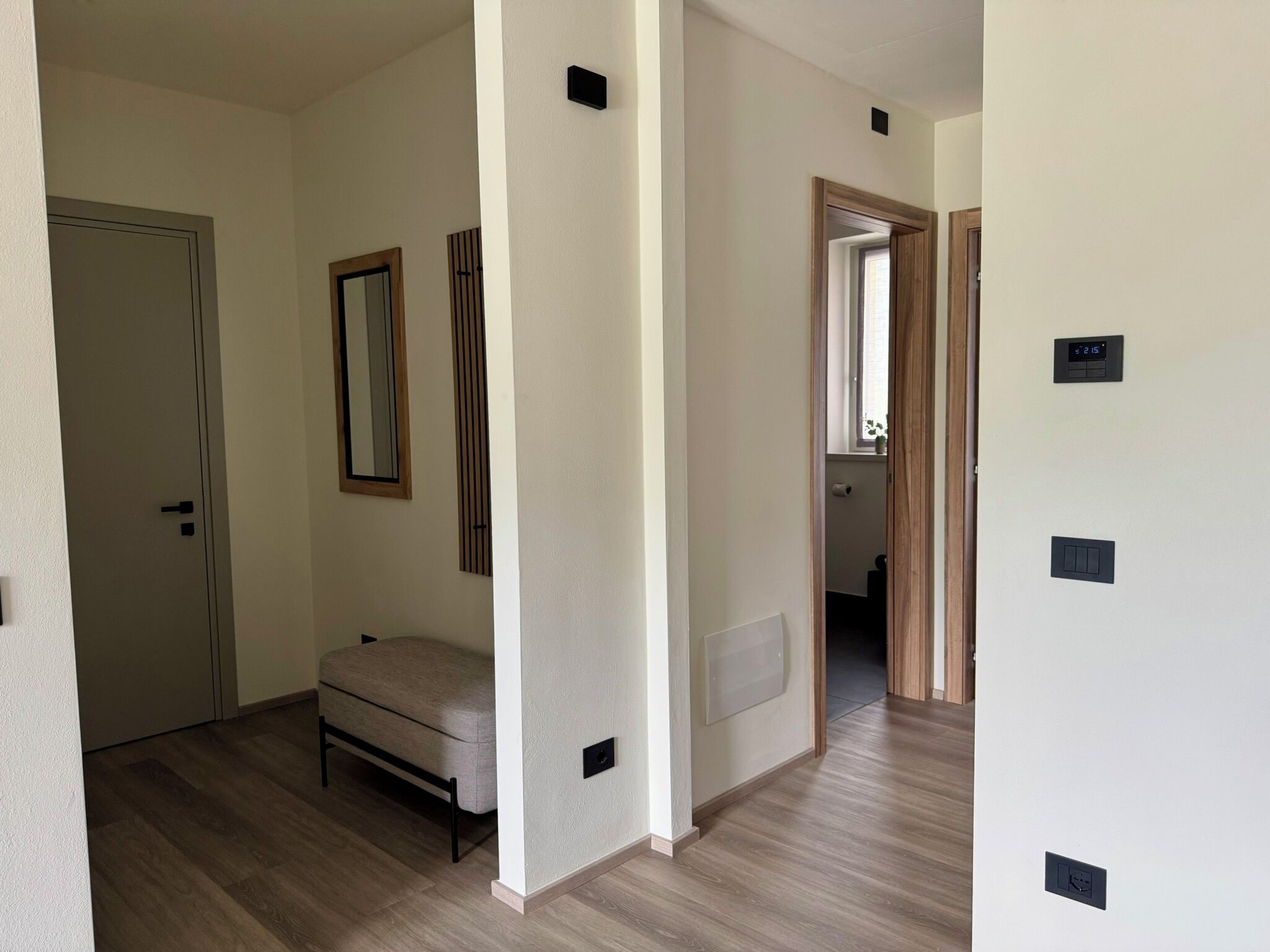Een kamer met een bed, een deur, een spiegel en een thermostaat aan de muur.