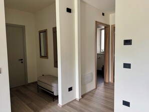 A room with a bed, a door, a mirror, and a thermostat on the wall. - Apartment 3 – Venezia (Tremosine sul Garda)