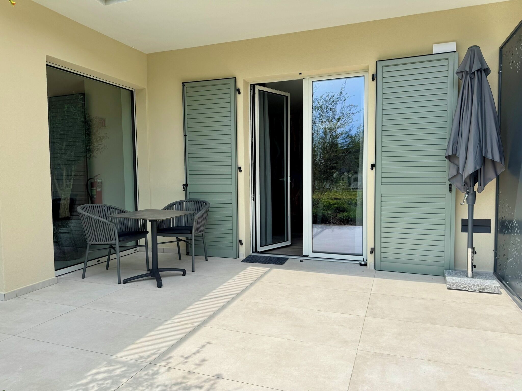 Ein überdachter Patio-Bereich mit Tisch und Stühlen, eine Schiebetür und ein überdachter Außenbereich mit Sitzgelegenheiten.