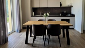 Una cocina moderna con una mesa de comedor, sillas y un jarrón de flores.
