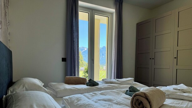 Una habitación de hotel con dos camas, un ventanal con cortinas y un armario.
