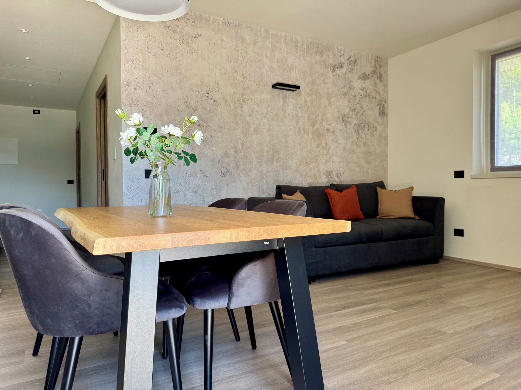 Un espace de vie moderne comprenant une table à manger, des chaises, un canapé et un vase décoratif avec des fleurs.