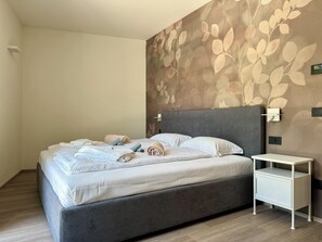 Ein modernes Schlafzimmer mit einem großen Bett, einem Nachttisch und einer Wandleuchte.