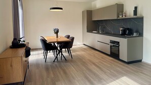Eine moderne Küche mit Essbereich, ausgestattet mit einem Holztisch, Stühlen und einer Pendelleuchte.