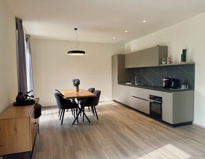 Una cocina moderna con comedor, que incluye una mesa de madera, sillas y una lámpara colgante.