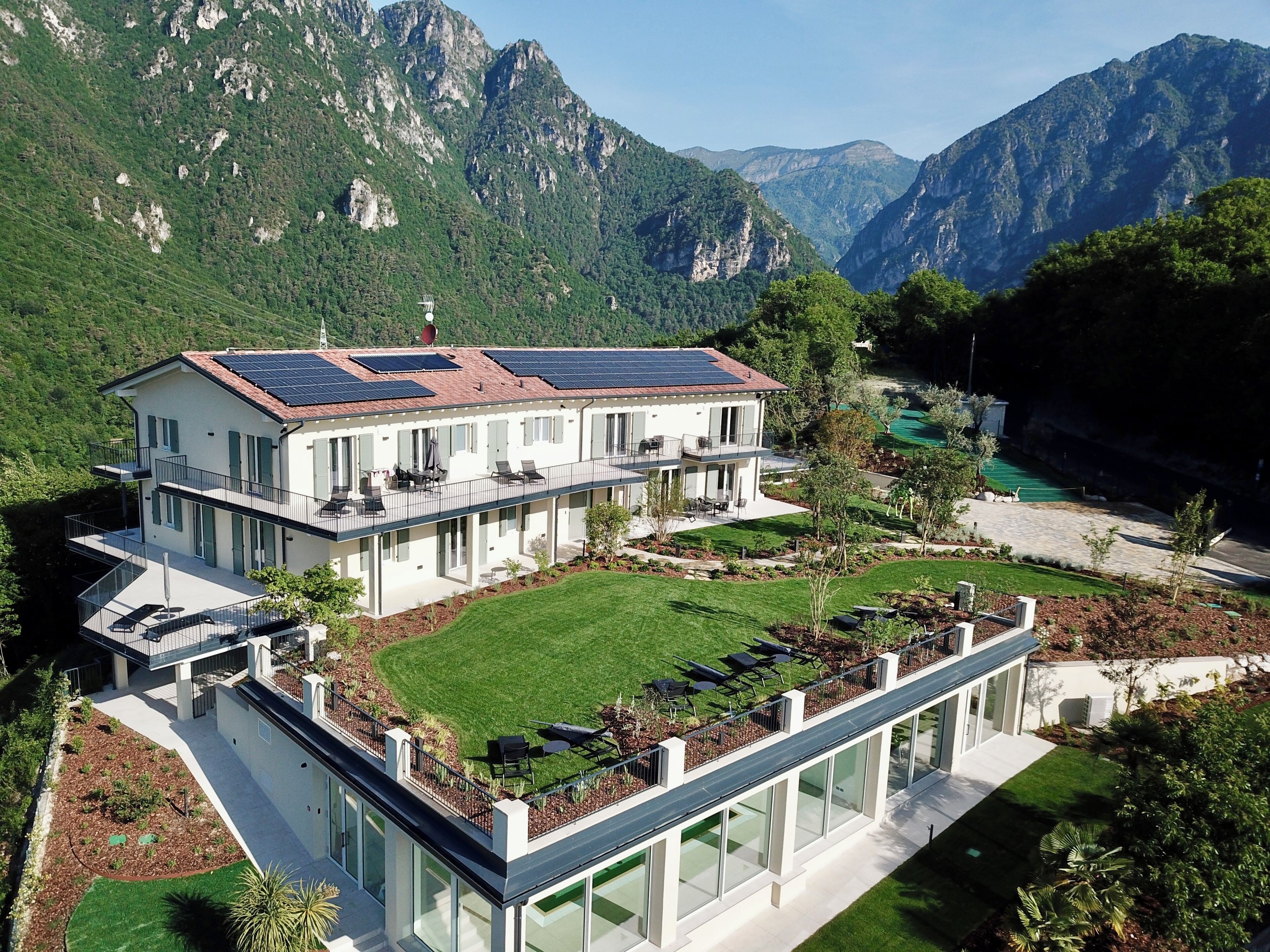 Ein modernes, zweistöckiges Haus mit flachem Dach, Solaranlage und einem großen Glaswintergarten.