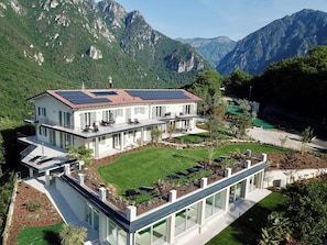 Ein modernes, zweistöckiges Haus mit flachem Dach, Solaranlage und einem großen Glaswintergarten.