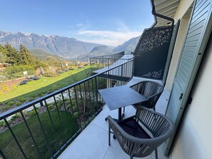 Ein Balkon mit Tisch und Stühlen, mit Blick auf eine Berglandschaft.