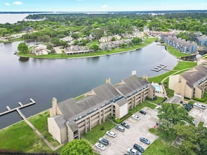 Un immeuble à plusieurs étages avec un parking et un lac en arrière-plan.