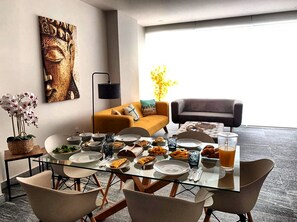 A dining area with a glass table, chairs, and a variety of dishes and drinks. - Spacious 3-bedroom apartment in beautiful Cancún with AC, Gym and rooftop Pool (Cancún)