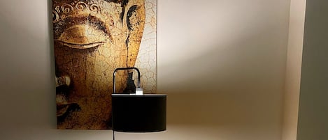 A room with a yellow sofa, a black floor lamp, and a wall-mounted artwork.