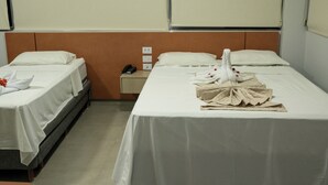Habitación de hotel con dos camas, una mesita de noche y un teléfono.