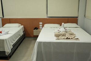 Habitación de hotel con dos camas, una mesita de noche y un teléfono.
