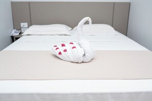 Una cama bien hecha con una toalla con forma de cisne sobre la colcha.