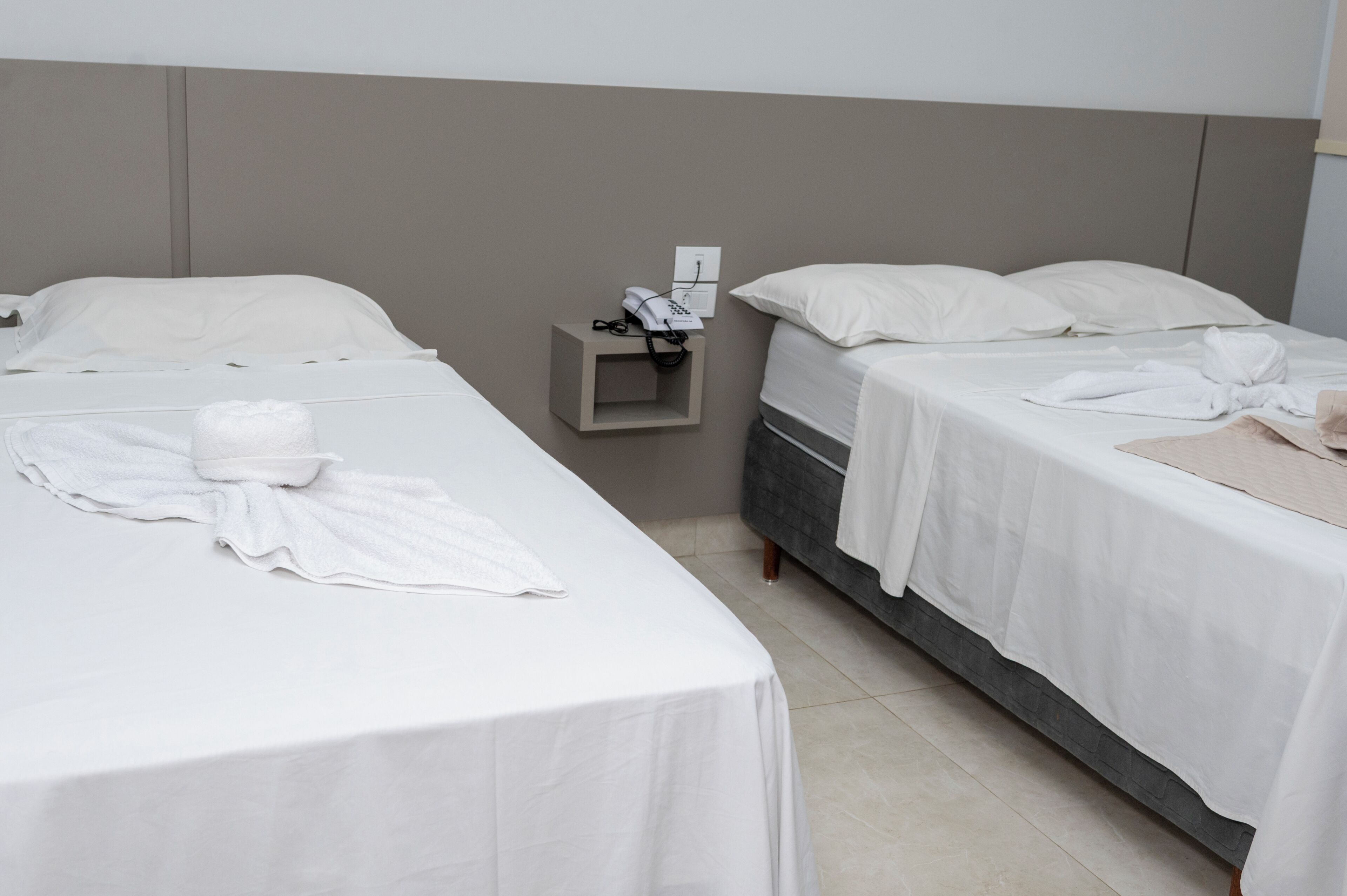Habitación de hotel con dos camas, una mesita de noche con un teléfono y una toalla sobre la cama.