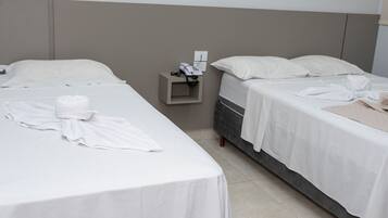 Habitación de hotel con dos camas, una mesita de noche con un teléfono y una toalla sobre la cama.