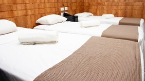 Habitación de hotel con dos camas, cada una con ropa de cama blanca y una manta marrón.