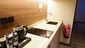 A compact kitchenette with a stove, sink, and a fire extinguisher mounted on the wall. - VISION TABUK (TABUK)