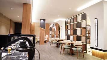 A modern interior with wooden paneling, a central seating area with tables and chairs, and recessed ceiling lighting.
