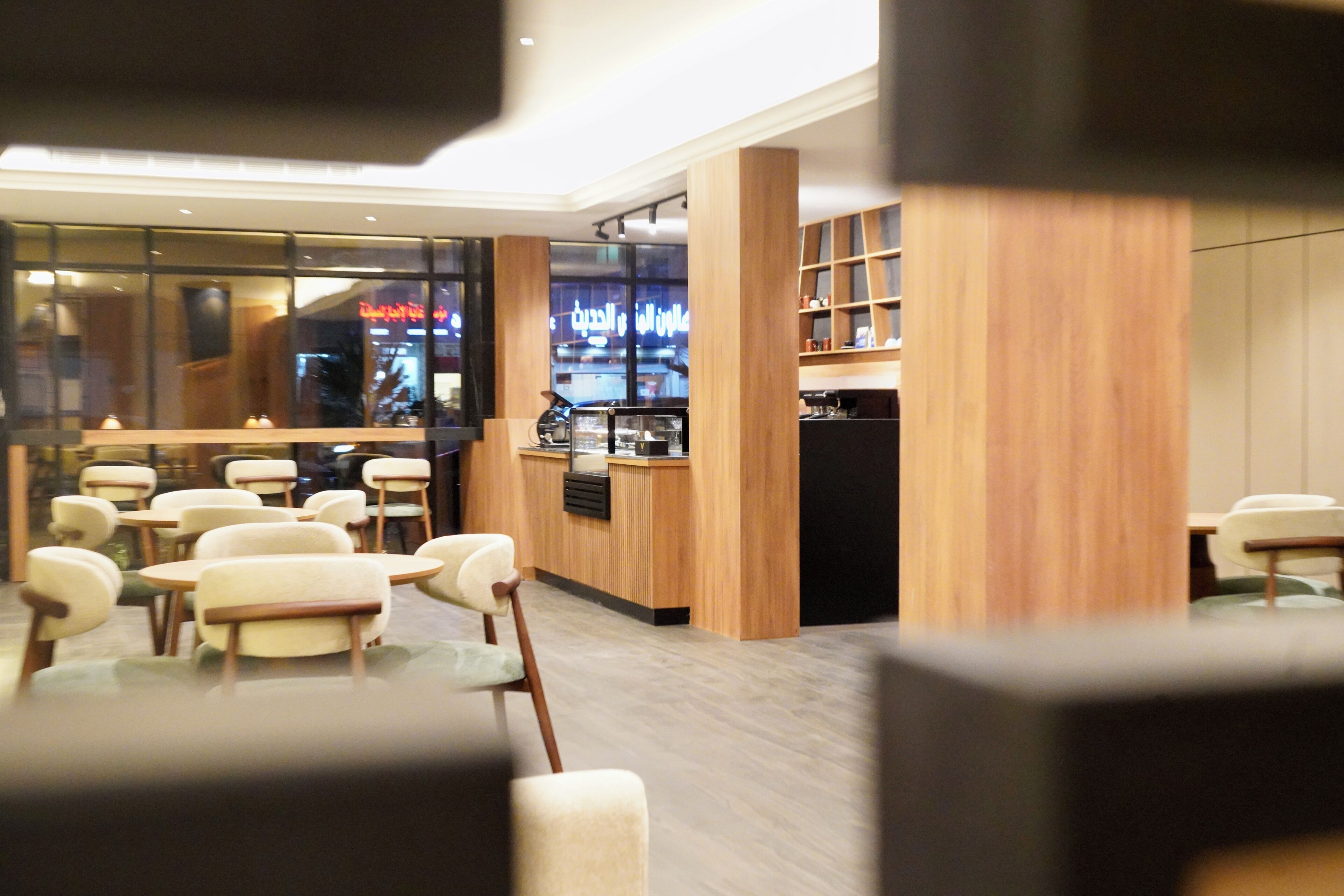 A modern cafe interior with wooden accents, a counter, and multiple seating areas.