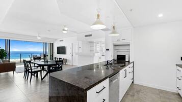 A modern kitchen with a large island, white cabinetry, and a view of the ocean.