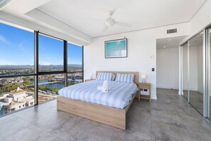 A modern bedroom with a large bed, a view of a cityscape, and a balcony.
