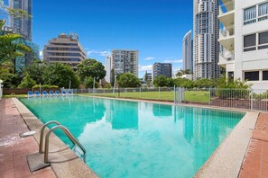 A swimming pool with a metal ladder, surrounded by a fence, and adjacent to high-rise buildings. - Central 2B Apartment Parking. Wi-Fi. Views. (Surfers Paradise)